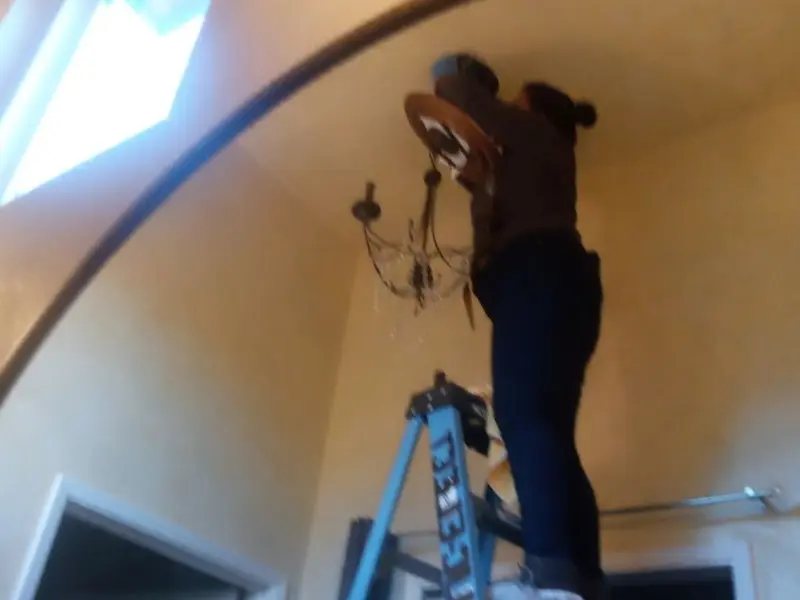 Electrician installing a chandelier in a Hideaway residence